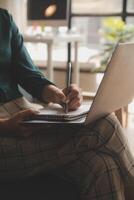Distracted from work worried young woman sitting on couch with laptop, thinking of problems. Pensive unmotivated lady looking at window, feeling lack of energy, doing remote freelance tasks at home. photo