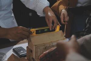 Team of multiethnic architects working on construction plans in meeting room. Engineers discussing on project in office. Mature businessman and woman standing around table working on blueprint. photo
