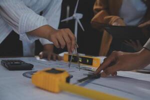 Team of multiethnic architects working on construction plans in meeting room. Engineers discussing on project in office. Mature businessman and woman standing around table working on blueprint. photo