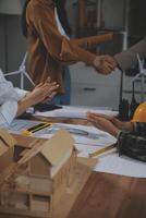 Construction team shake hands greeting start new project plan behind yellow helmet on desk in office center to consults about their building project. in sun light photo