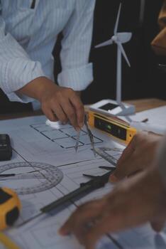 Team of multiethnic architects working on construction plans in meeting room. Engineers discussing on project in office. Mature businessman and woman standing around table working on blueprint. photo