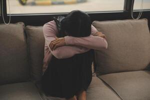 Depressed woman sitting alone on the bed with hands on head feel stress, sad and worried in the dark bedroom and low light environment photo