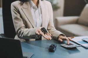 Business car rental company service, Close up hand of agent dealer giving, holding car key to customer renter, new owner after signed rental, purchase contract in document, vehicle sales agreement. photo