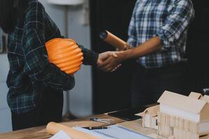 Architect and construction engineer holding hands while working for teamwork and cooperation concept after completing an agreement at construction site, office, close-up image photo