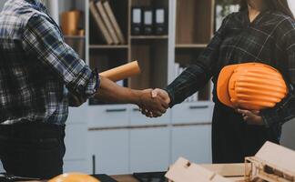 Architect and construction engineer holding hands while working for teamwork and cooperation concept after completing an agreement at construction site, office, close-up image photo
