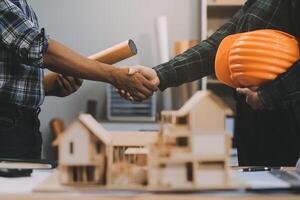 Architect and construction engineer holding hands while working for teamwork and cooperation concept after completing an agreement at construction site, office, close-up image photo