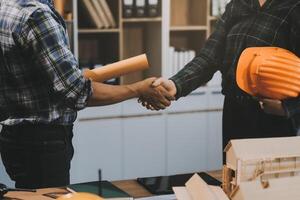 Architect and construction engineer holding hands while working for teamwork and cooperation concept after completing an agreement at construction site, office, close-up image photo