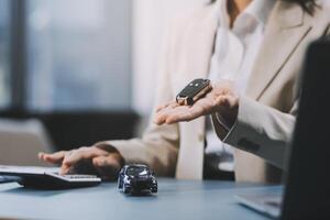 Business car rental company service, Close up hand of agent dealer giving, holding car key to customer renter, new owner after signed rental, purchase contract in document, vehicle sales agreement. photo
