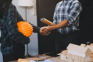 Architect and construction engineer holding hands while working for teamwork and cooperation concept after completing an agreement at construction site, office, close-up image photo