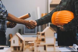 Architect and construction engineer holding hands while working for teamwork and cooperation concept after completing an agreement at construction site, office, close-up image photo
