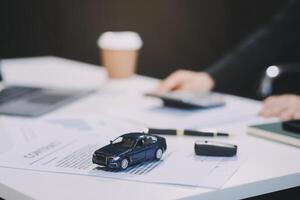Car sales representative gives keys to new car owner, concept for car rental Focus on the key. Pick up the key. Close-up of the key transfer from the new machine to the buyer. photo