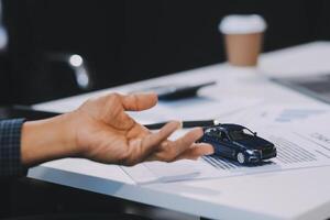 Car sales representative gives keys to new car owner, concept for car rental Focus on the key. Pick up the key. Close-up of the key transfer from the new machine to the buyer. photo