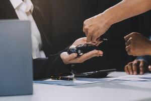 Car sales representative gives keys to new car owner, concept for car rental Focus on the key. Pick up the key. Close-up of the key transfer from the new machine to the buyer. photo