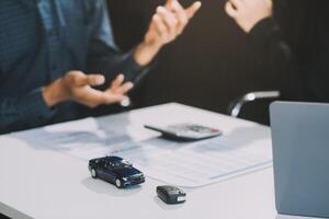 Car sales representative gives keys to new car owner, concept for car rental Focus on the key. Pick up the key. Close-up of the key transfer from the new machine to the buyer. photo