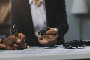 Car sales representative gives keys to new car owner, concept for car rental Focus on the key. Pick up the key. Close-up of the key transfer from the new machine to the buyer. photo