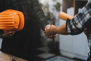 Architect and construction engineer holding hands while working for teamwork and cooperation concept after completing an agreement at construction site, office, close-up image photo
