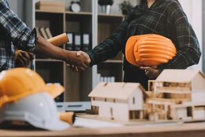 Architect and construction engineer holding hands while working for teamwork and cooperation concept after completing an agreement at construction site, office, close-up image photo