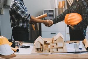 Architect and construction engineer holding hands while working for teamwork and cooperation concept after completing an agreement at construction site, office, close-up image photo