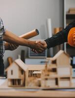 Architect and construction engineer holding hands while working for teamwork and cooperation concept after completing an agreement at construction site, office, close-up image photo
