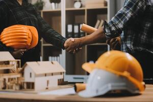 Architect and construction engineer holding hands while working for teamwork and cooperation concept after completing an agreement at construction site, office, close-up image photo