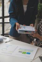 Group of confident business people point to graphs and charts to analyze market data, balance sheet, account, net profit to plan new sales strategies to increase production capacity. photo