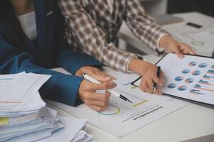 Group of confident business people point to graphs and charts to analyze market data, balance sheet, account, net profit to plan new sales strategies to increase production capacity. photo