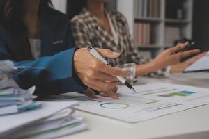 Group of confident business people point to graphs and charts to analyze market data, balance sheet, account, net profit to plan new sales strategies to increase production capacity. photo