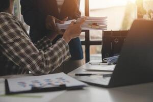Group of confident business people point to graphs and charts to analyze market data, balance sheet, account, net profit to plan new sales strategies to increase production capacity. photo