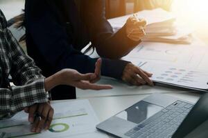 Group of confident business people point to graphs and charts to analyze market data, balance sheet, account, net profit to plan new sales strategies to increase production capacity. photo