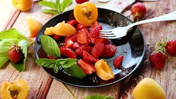 fresh fruit salad of ripe strawberries and apricots, on a light wooden table video