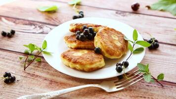 Fried curd cheese pancakes with black currants, on a wooden table video