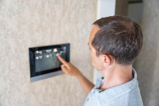 Man using tablet panel application for control smart home living. Wireless device controller for home automation IoT on the wall. High quality photo