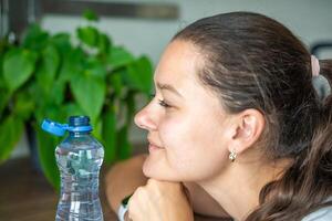Young woman with bottle with stationary plastic cap. The new design means the cap remains attached to the bottle after opening, making the entire package easier to collect and recycle. photo