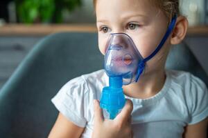 Close up view of little girl are sitting and holding a nebulizer mask leaning against the face, airway treatment concept photo
