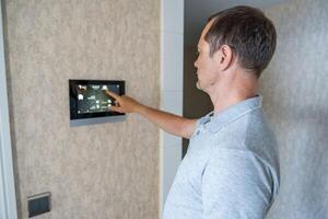 Man using tablet panel application for control smart home living. Wireless device controller for home automation IoT on the wall. High quality photo
