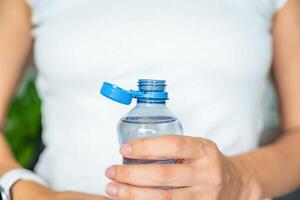 Bottle with stationary plastic cap in woman hand. The new design means the cap remains attached to the bottle after opening, making the entire package easier to collect and recycle. High quality photo