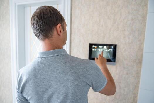 Man using tablet panel application for control smart home living. Wireless device controller for home automation IoT on the wall. High quality photo