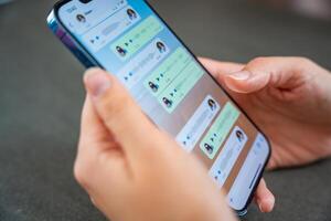 Prague, Czech republic - May 2, 2024. Woman holding iPhone with chat application WhatsApp on the screen, using mobile application for voice messaging at home. High quality photo