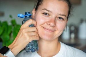 Young woman with bottle with stationary plastic cap. The new design means the cap remains attached to the bottle after opening, making the entire package easier to collect and recycle. photo