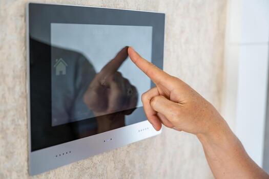 View of hand of man using tablet panel application for control smart home living. Wireless device controller for home automation IoT on the wall. High quality photo