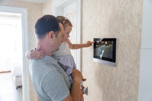 Daughter in her father using tablet panel application for control smart home living. Wireless device controller for home automation IoT on the wall. High quality photo