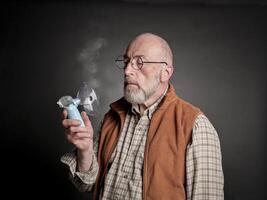 senior man using a portable handheld nebulizer photo
