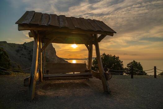 un de madera banco es sentado debajo un de madera abrigo con un ver de el océano. el banco es vacío y el cielo es nublado. foto