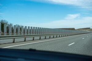 A road with a long line of metal posts with red hearts on them. The road is empty and the sky is clear. photo