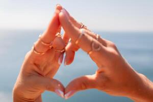 A woman's hands are holding each other in a heart shape, with the fingers of her right hand touching the fingers of her left hand. Concept of love and connection between the two hands. photo
