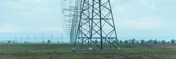 High voltage towers with sky background. Power line support with wires for electricity transmission. High voltage grid tower with wire cable at distribution station. Energy industry, energy saving photo