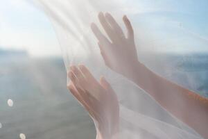 A woman's hands are shown in a white veil, with the sun shining on them. Concept of peace and serenity, as the woman's hands are open and relaxed. photo