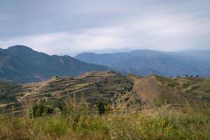 A mountain range with a cloudy sky in the background. The sky is overcast and the mountains are covered in trees. photo