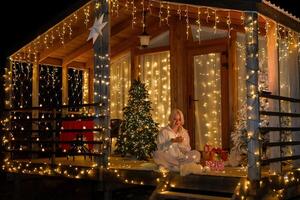Woman by Christmas tree. Festive setting. Illustrating holiday cheer and celebration. She is posing for a picture, and there are presents nearby, adding to the festive atmosphere. photo