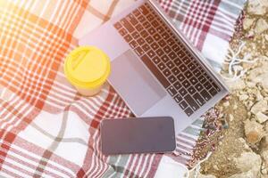 Laptop on blanket with ocean view. Illustrating serene outdoor laptop use. Freelancer enjoying their time outdoors while working or browsing the internet. photo